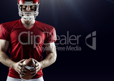 American football player standing with ball against black background