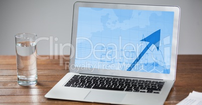 Laptop and glass of water on wooden table