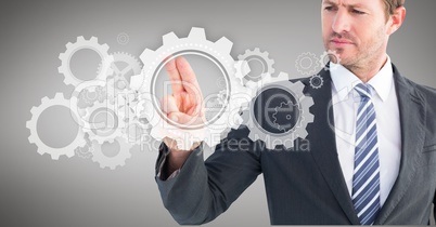 Businessman touching cog wheel on digital screen against grey background