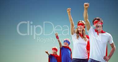 Family in superhero costumes standing with arms raised