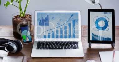 Laptop and digital tablet with graph charts on wooden table