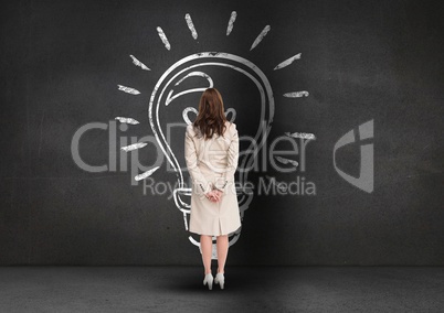 Rear view of businesswoman looking at innovative bulb on grey background