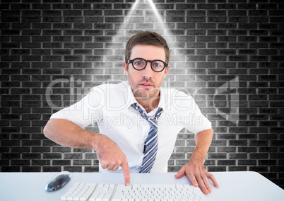 Man in spectacles typing on keyboard against brick wall background