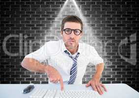 Man in spectacles typing on keyboard against brick wall background