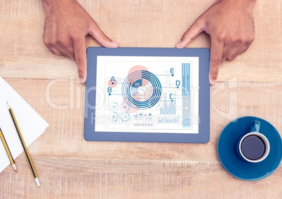 Mans hand holding digital tablet showing graph and chart on wooden table