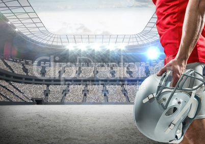 American football player standing with helmet against digitally composite stadium