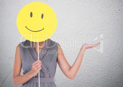 Woman covering her face with smiley and gesturing