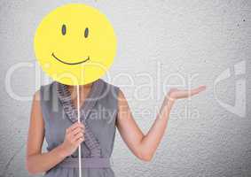 Woman covering her face with smiley and gesturing
