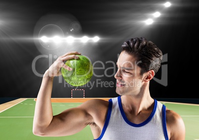 Athlete flxing his arm while holding handball against stadium in background