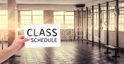 Hand holding placard with text class schedule in the gym
