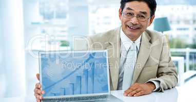 Portrait of smiling businessman showing graph on laptop