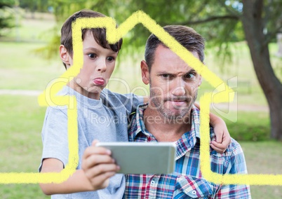 Dad and son taking a selfie outdoors against house outline in background