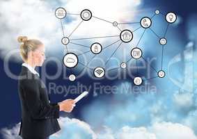 Side view of businesswoman using digital tablet with connecting icons and clouds in background