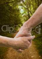 Close-up of couple holding hands against footpath