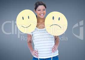 Cheerful woman holding smiley and sad face
