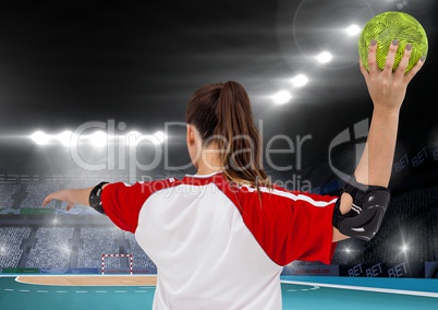 Female athlete throwing handball against stadium in background