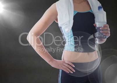 Fit woman holding water bottle against black background