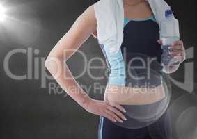 Fit woman holding water bottle against black background