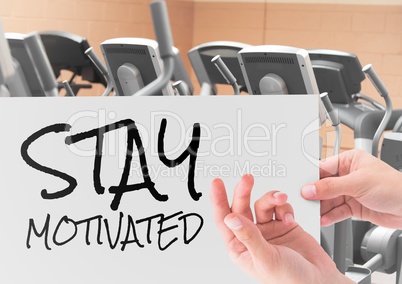 Female hand holding placard with text stay motivated in gym