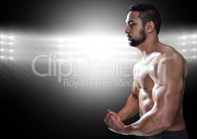 Muscular man posing against black illuminated background