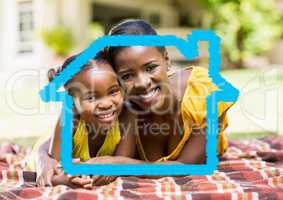 Mother and daughter laying in the park against house outline in background