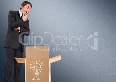 Businessman looking in cardboard box with electric bulb drawing on it