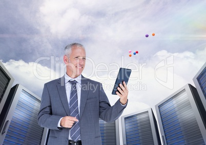 Businessman using digital tablet against server systems in sky