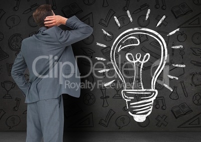 Thoughtful businessman looking at bulb sketch on blackboard