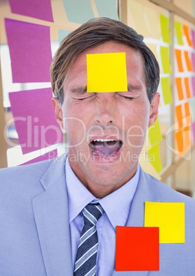Stressed businessman with sticky notes on forehead