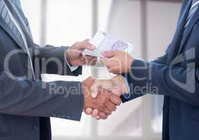 Businessman bribing partner while shaking hands