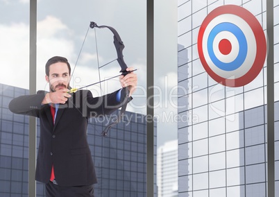 Businessman aiming at the target board against office buildings in background