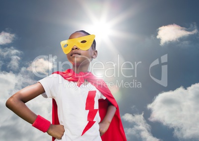 Girl in superhero costume with hands on her hips against sky in background