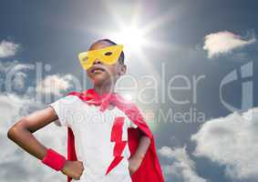 Girl in superhero costume with hands on her hips against sky in background