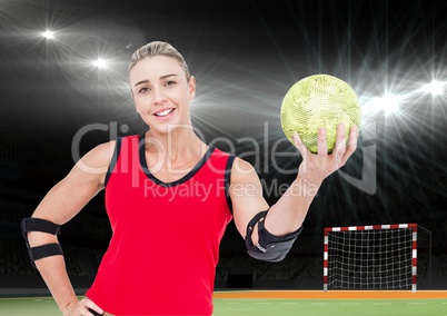 Female athlete holding handball against stadium in background