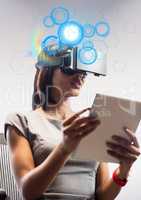 Woman sitting on chair while using virtual reality headset and digital tablet