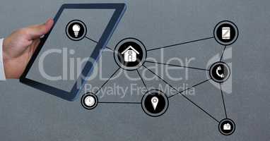 Hand holding digital tablet with networking icons against grey background