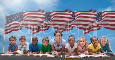 Happy teacher and students lying with book against american flag
