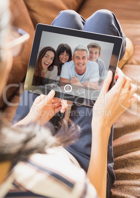 Woman sitting on sofa having video call with family on digital tablet