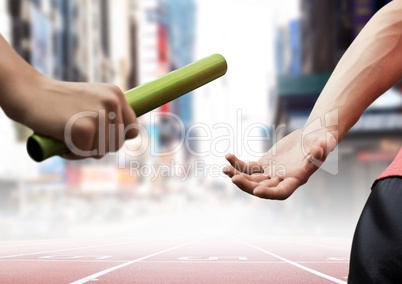 Athletes passing the baton during relay race against city buildings