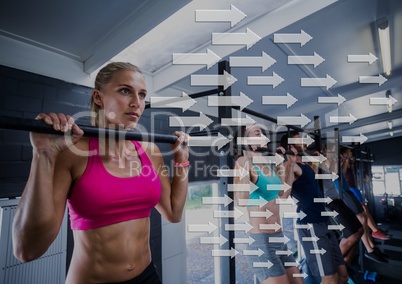 Fit woman performing pull up exercise in gym against direction arrows in background