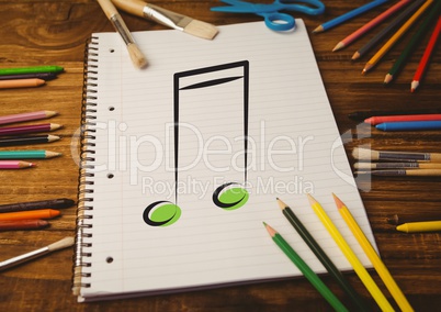 Spiral notepad with music sign and colored pencils on table