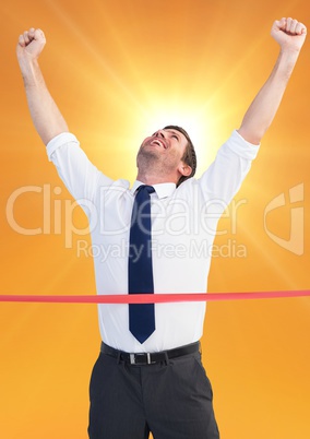 Excited businessman crossing the finish line against bright sunlight