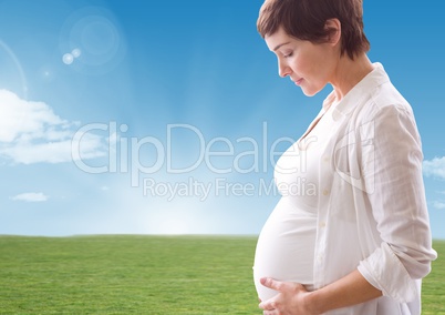 Pregnant woman looking a her belly against landscape