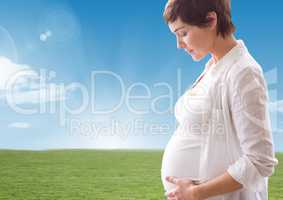 Pregnant woman looking a her belly against landscape