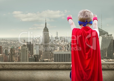 Boy pretending to be a superhero against cityscape in background