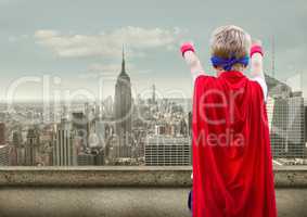 Boy pretending to be a superhero against cityscape in background