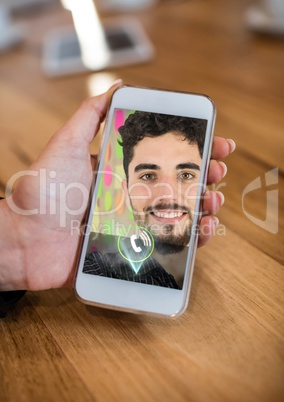 Hand holding mobile phone displaying man on video call screen