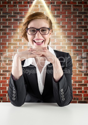 Businesswoman smiling on her desk against brick wall in background