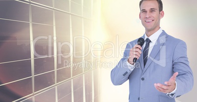 Businessman speaking with microphone against city building