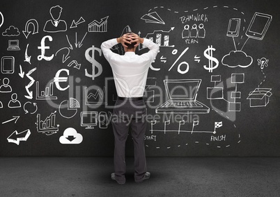 Confused businessman standing against business symbols in background